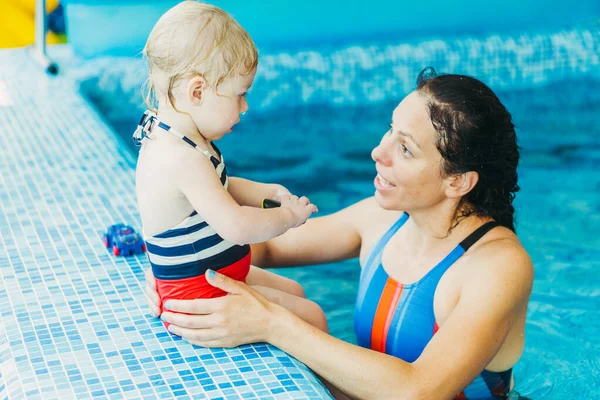 Piscina. Mamá enseña a un niño pequeño a nadar en la piscina . — Foto de Stock