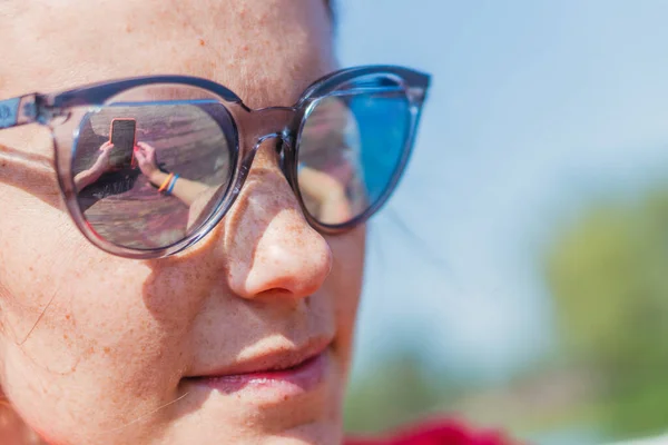 Mobile phone. A woman in sunglasses looks at a mobile phone. — Stock Photo, Image