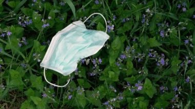 Tıbbi maske. Atılmış tıbbi maske yeşil bir çimenlikte yatıyor..