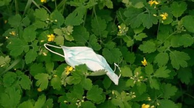 Tıbbi maske. Atılmış tıbbi maske yeşil bir çimenlikte yatıyor..