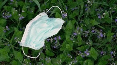Tıbbi maske. Atılmış tıbbi maske yeşil bir çimenlikte yatıyor..