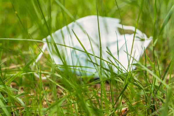 医疗面罩这个废弃的医疗面具躺在绿色的草坪上 — 图库照片