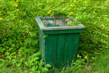 Çöp. Yeşil bir parkta duran ahşap bir çöp kutusu..