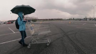 Alışveriş arabası. Tıbbi maskeli bir kadın alışveriş arabası taşıyor..