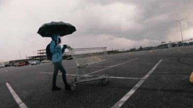 Alışveriş arabası. Tıbbi maskeli bir kadın alışveriş arabası taşıyor..