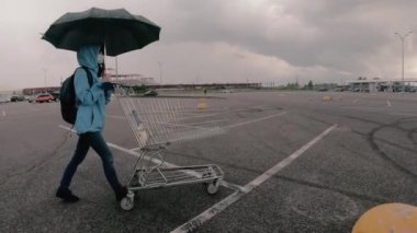 Alışveriş arabası. Tıbbi maskeli bir kadın alışveriş arabası taşıyor..