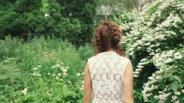 Yasemin bitkisi. Genç bir kadın yasemin bitkisinin yanında yürüyor..