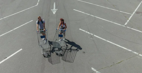 ショッピングカート ショッピングカートを持った男と女が蒸留所を通り店へ — ストック写真
