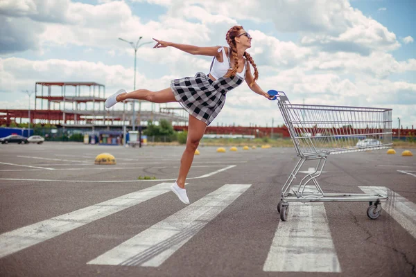 Supermarket trolley. A woman is carrying a trolley for a supermarket.