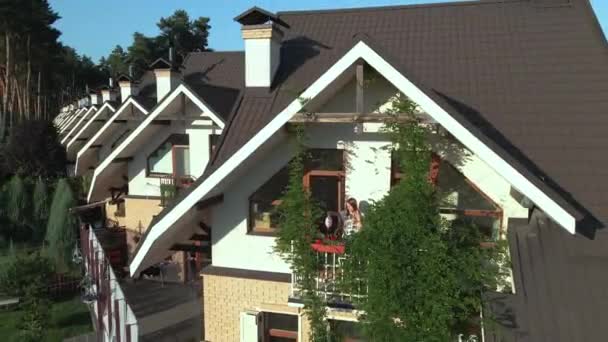 Cottage. A woman on a loggia watering flowers. Aerial view. — Stock Footage Cottage Woman Loggia Watering Flowers Aerial View Stock Footage