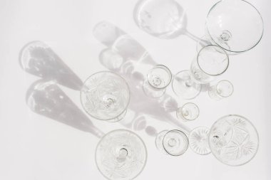 Beyaz arka planda farklı boş bardaklar. Doğrudan güneş ışığı. Üst görünüm, düz görünüm, kopyalama alanı.