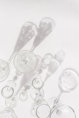 Beyaz arka planda farklı boş bardaklar. Doğrudan güneş ışığı. Üst görünüm, düz görünüm, kopyalama alanı.