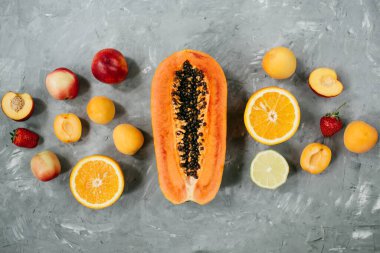 Meyvelerden oluşan yaratıcı bir düzen. Düz yatıyordu. Papaya, çilek, kayısı, nektarin, avokado, gri arka planda portakal ve limon. Yüksek kalite fotoğraf