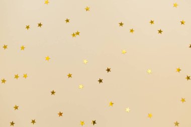 Bej renkli kağıt üzerine altın konfeti. Bayram arkaplanı. Doğum günü, Noel, Sevgililer Günü, Yeni Yıl. Düz konum, üst görünüm, kopyalama alanı.