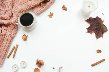 Örgü süveter, bir fincan kahve, sonbahar yaprakları, tarçın çubukları, beyaz arka planda mumlar. Sonbahar kompozisyonu. Düz konum, üst görünüm, kopyalama alanı