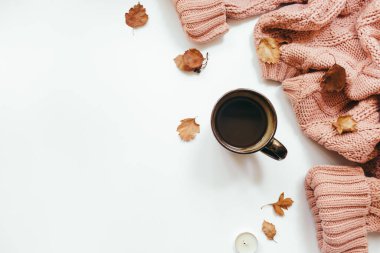 Örgü süveter, bir fincan kahve, sonbahar yaprakları, tarçın çubukları, beyaz arka planda mumlar. Sonbahar kompozisyonu. Düz konum, üst görünüm, kopyalama alanı