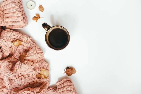 Knitted sweater, cup of coffee, autumn leaves, cinnamon sticks, candles on white background. Autumn composition. Flat lay, top view, copy space