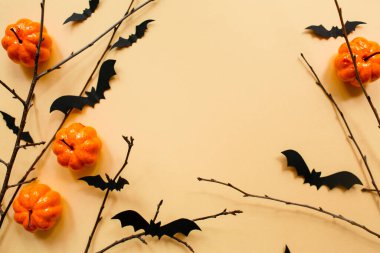 Pastel bej arka planda balkabağı, yarasalar ve dallarla Cadılar Bayramı süslemeleri. Cadılar Bayramı konsepti Düz konum, üst görünüm, kopyalama alanı