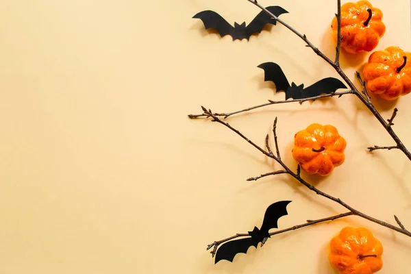 Decorazioni Halloween con zucca e pipistrelli e rami su sfondo beige pastello. Concetto Halloween. Layout piatto, vista dall'alto, spazio di copia — Foto Stock