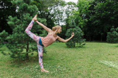 Güzel genç bayan parkta yoga yapıyor..