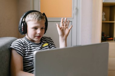 Erkek öğrenci video konferansı, öğretmeniyle birlikte evdeki oturma odasında. Evde eğitim ve uzak öğrenim, çevrimiçi, eğitim ve İnternet.