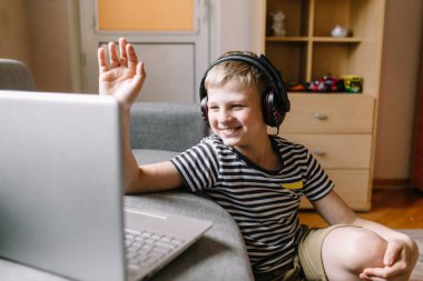 Erkek öğrenci video konferansı, öğretmeniyle birlikte evdeki oturma odasında. Evde eğitim ve uzak öğrenim, çevrimiçi, eğitim ve İnternet.