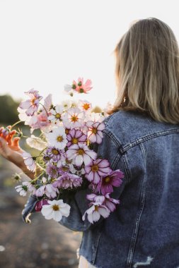 Elinde bir buket çiçek olan genç bir kadının arka plan görüntüsü. Yaz havası konsepti. Yüksek kalite fotoğraf