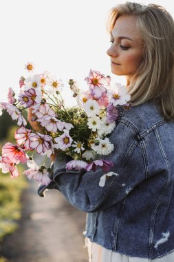 Çiçek buketi kozmos ellerde kadın gün ışığında. Yaz havası kavramı.