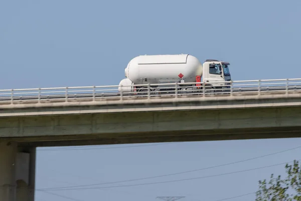 Beyaz yakıt tankı açık bir günde üst geçit köprüsünde ilerliyor.