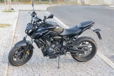 Çağdaş siyah Yamaha Mt. 07 motosikleti kaldırım taşı bir caddeye park edilmiş, parlak tasarımı ve güçlü motoru sergileniyor.