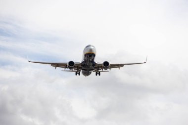 İniş pistine yaklaşan yolcu uçağı. Arka planda bulutlu bir gökyüzü var.