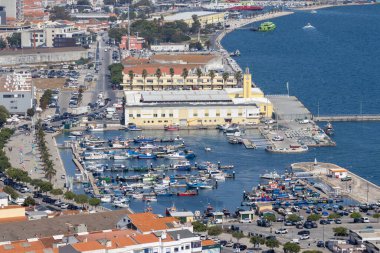 Limanda demirlemiş renkli tekneleri ve kıyı boyunca uzanan şehir manzarası olan setubal, Portekiz 'deki Doca de Recreio balıkçılık limanının havadan görüntüsü.