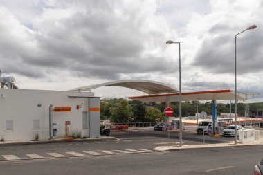 Modern galp gas station with a distinctive orange canopy under a cloudy sky, offering refueling services to passing vehicles