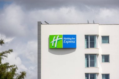 Holiday inn express logo displayed on a white building facade under a cloudy sky in alfragide, portugal