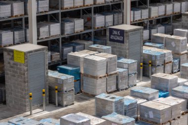 Pallets with construction materials like tiles and bricks are stored in a warehouse of a building materials store