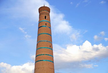 Mavi bulutlu gökyüzünün arka planına karşı minare. Özbekistan.