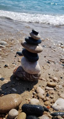 Kum kıyısı barışçıl deniz tatilinde farklı boyutlarda taş piramidi