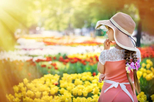 Beautiful Girl thinks and dreams against the background of a tulip meadow