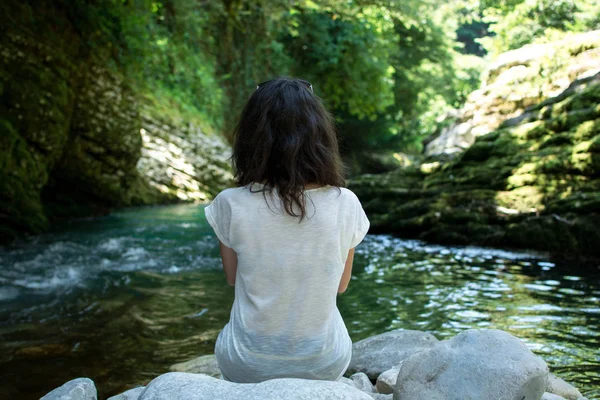 A menina perto do rio de montanha olha para a distância — Fotografia de Stock