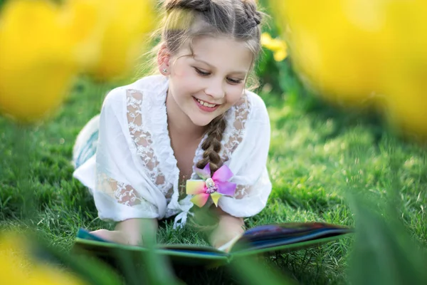 Bella ragazza con un sorriso legge un libro interessante — Foto Stock