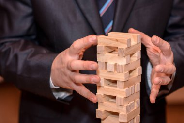 Alternatif risk kavramı, plan ve strateji iş. İşadamı el ahşap blokların bir kule tutmaya çalışırken.