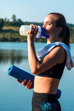 Güzel kız güzel doğanın bir arka plan üzerinde bir spor eğitimi sırasında su içiyor