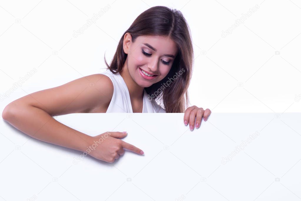 Beautiful happy girl, isolated on white background, shows a finger at a blank billboard.