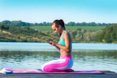 Eğitim bir mola sırasında genç güzel kız telefona bakar. Telefon, fitness, gençlik kavramı