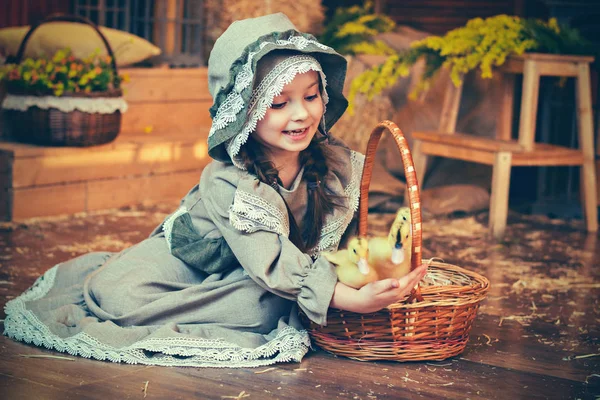 レトロな小さな幸せな女の子はアヒルの子と遊ぶ。イースターカードレトロなスタイル。カントリースタイル — ストック写真