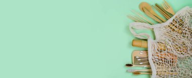 Sıfır atık. Eko torba, bambu diş fırçası, tarak, yemek pişirme, kulak çubuğu, yeşil arka planda yeşil yapraklar. Üst görünüm ya da düz katman. Metin için alanı kopyala. Banner