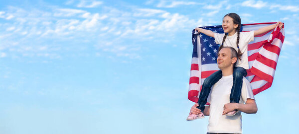 Счастливая дочь сидит на плечах своего отца и держит американский флаг над головой. День независимости США. Счастливой концепции будущего. Свободу. Космос для текстового баннера