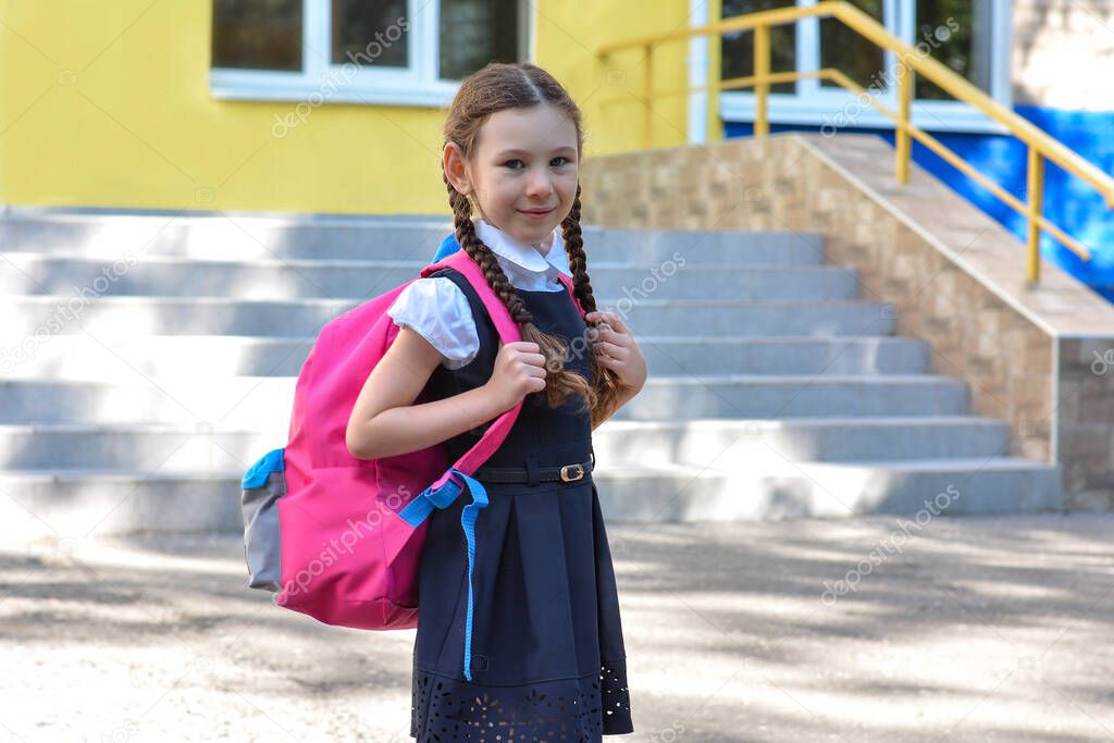 Back to school. Child going school after pandemic over.Portrait of a schoolgirl with a backpack against the background of the school.