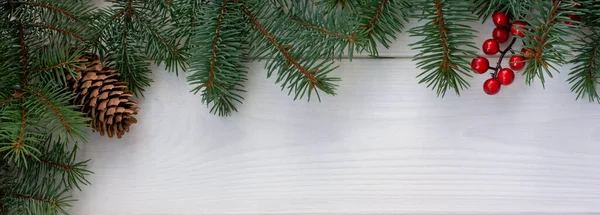 圣诞树分枝 有松果和红色浆果 白色木制背景 复制空间为您的文字 圣诞贺卡 — 图库照片