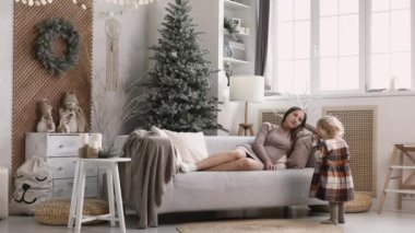 Anne ve kızı Noel sabahı eğleniyorlar. Değerli aile anı, genç anne Noel ağacının yanında kızıyla oynuyor..